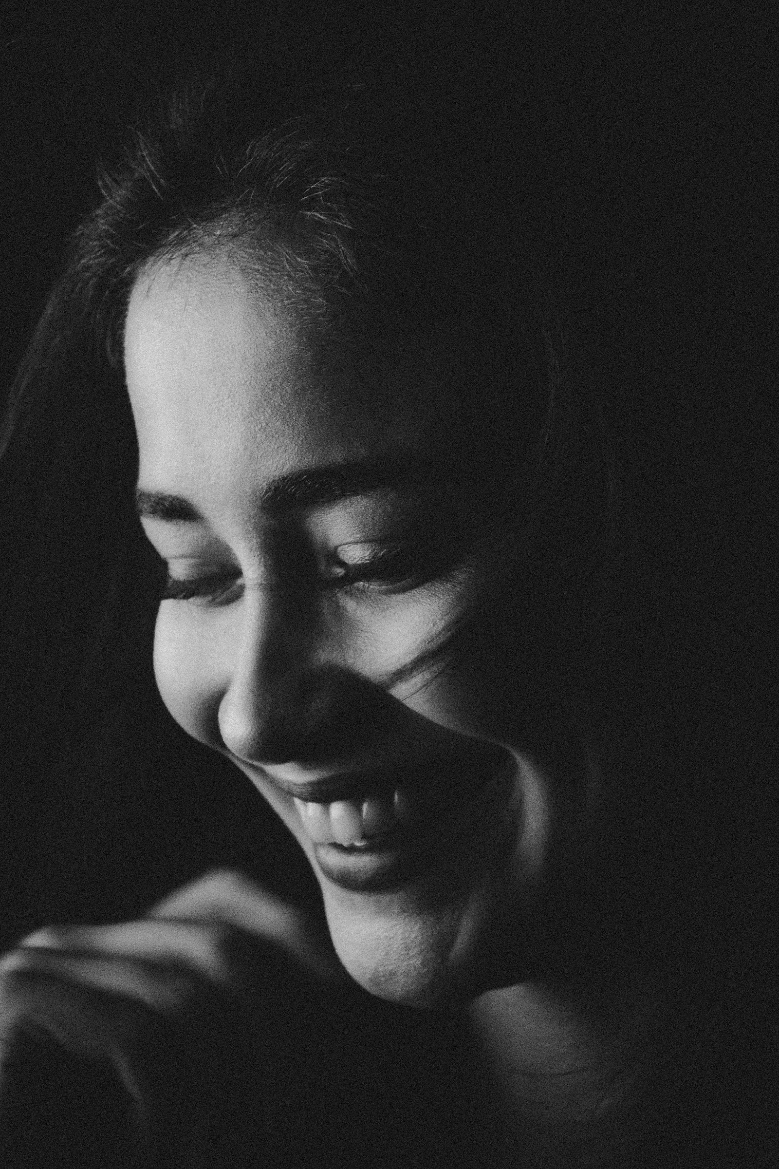 Black and white portrait of a woman laughing in dramatic side light