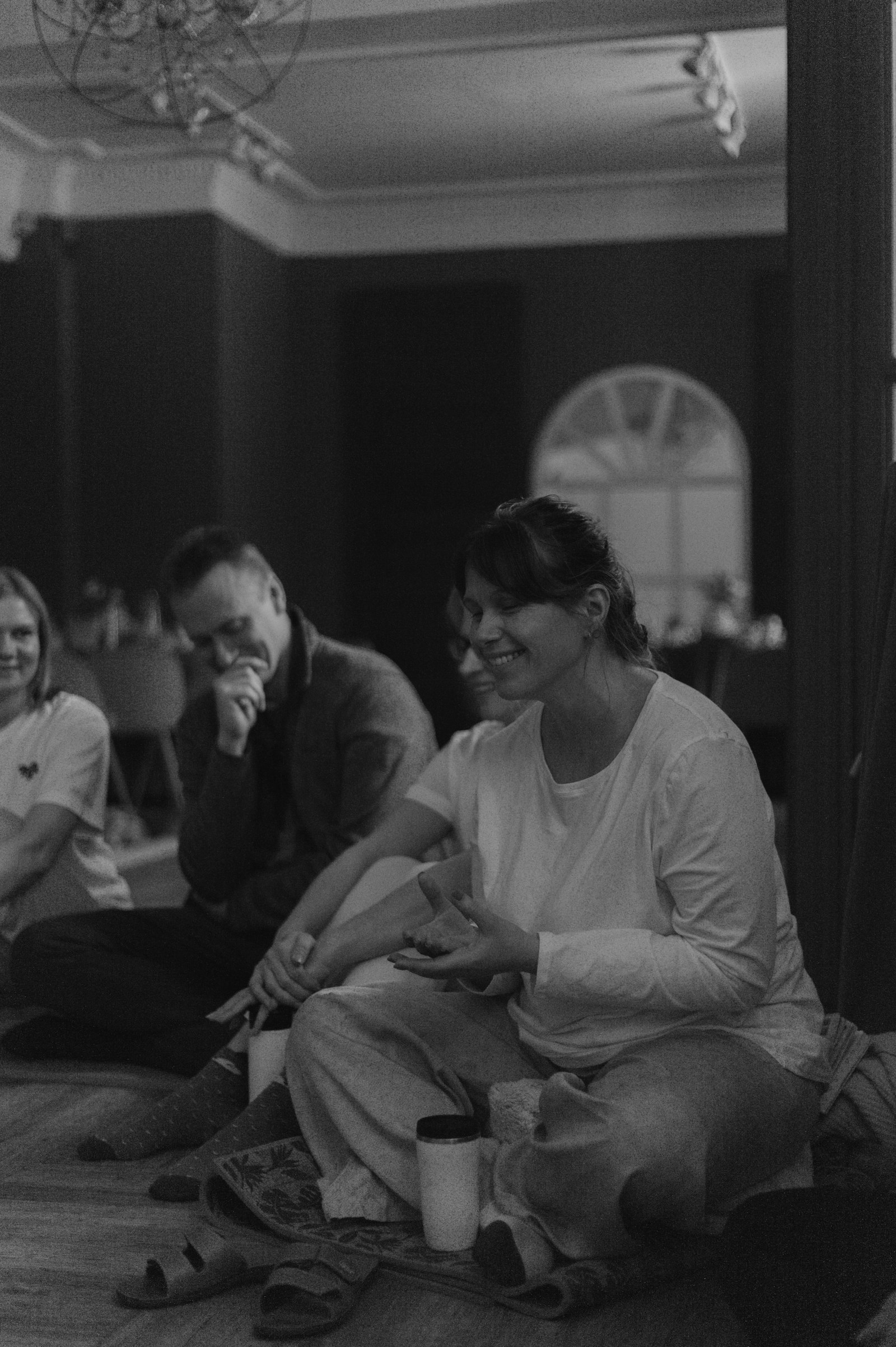 Black and white photograph of a workshop group sitting in a circle on the floor, laughing